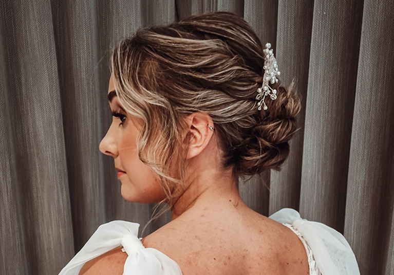 View of brides wavy updo with accessory from back